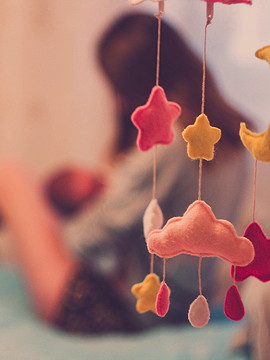 Vordergrund Baby Mobile im Hintergrund verschwommen Mutter am Stillen